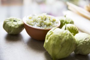 Tomatillos and a bowl of green salsa.
